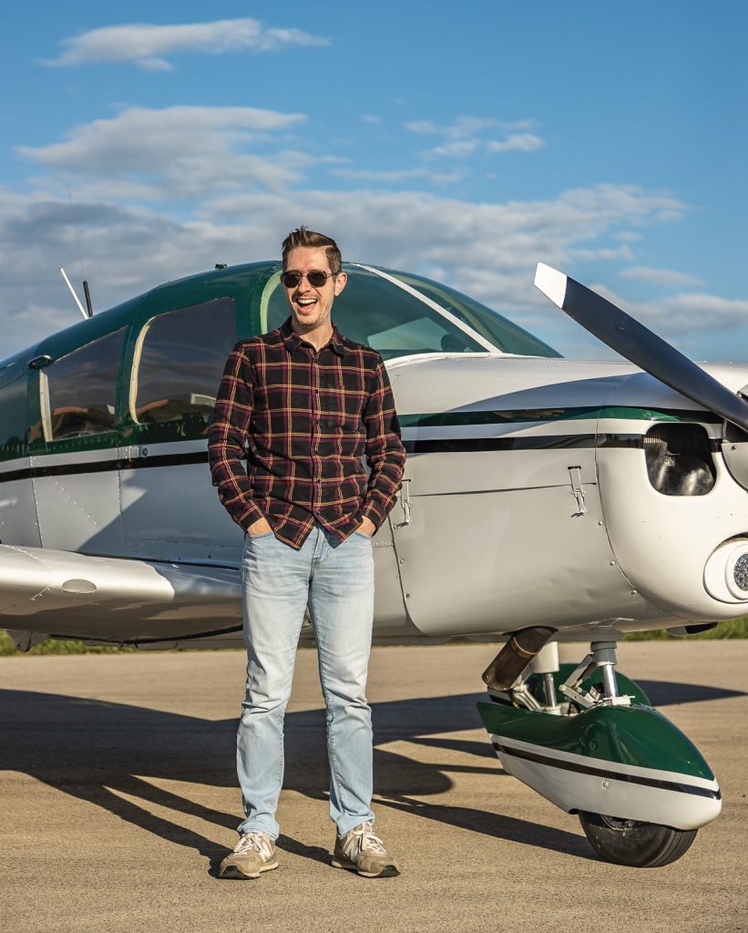 man smiling in front of his plane