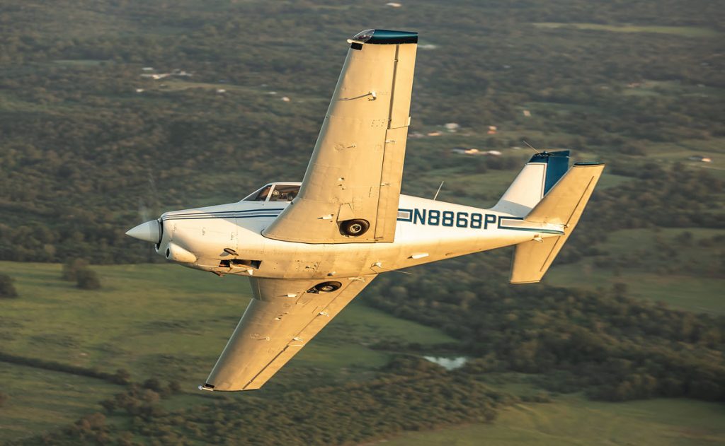 belly of 1966 Piper Comanche 260B in flight